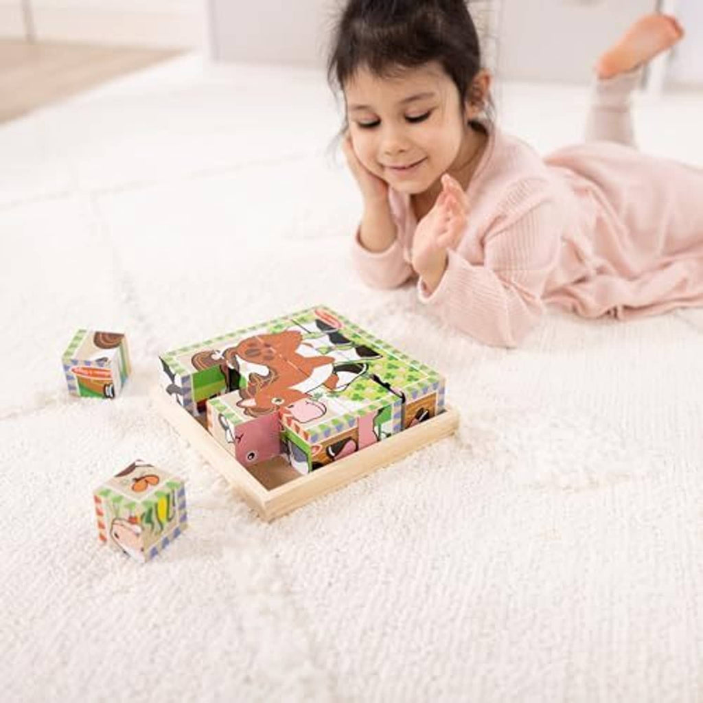 Child using a wooden tray farm cube puzzle with scattered cubes on the floor