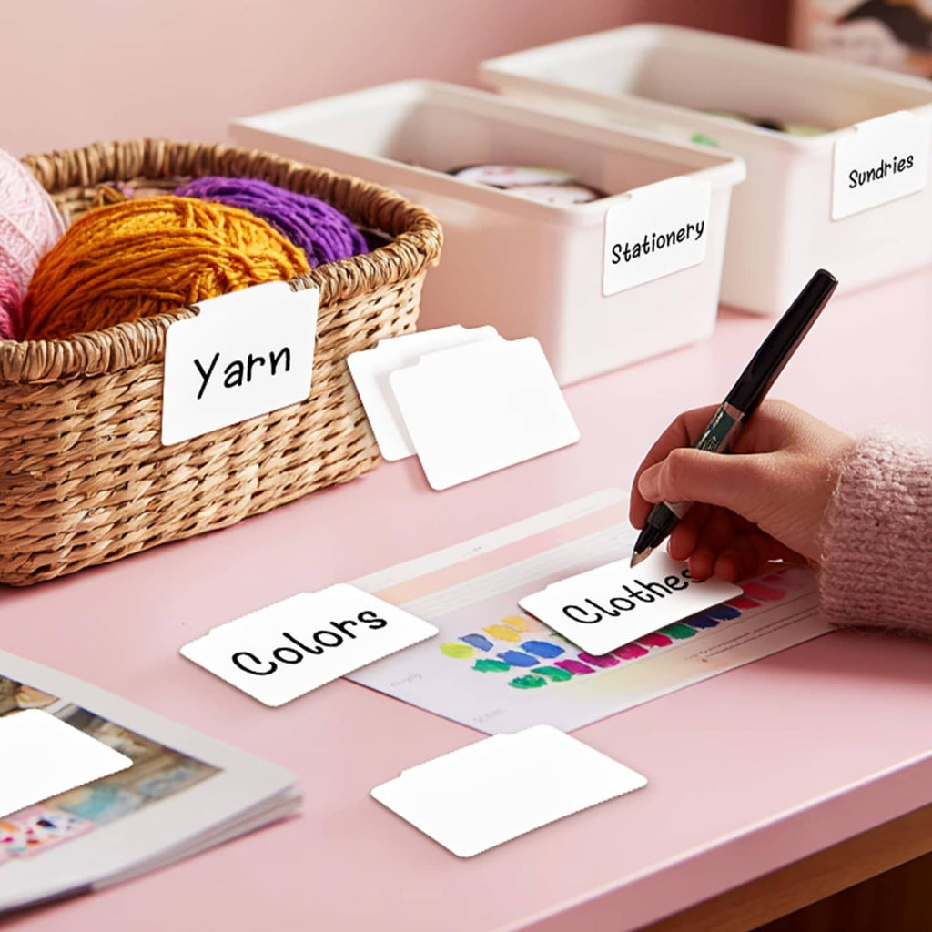 White storage label cards clipped to woven baskets for yarn, clothes, and stationery