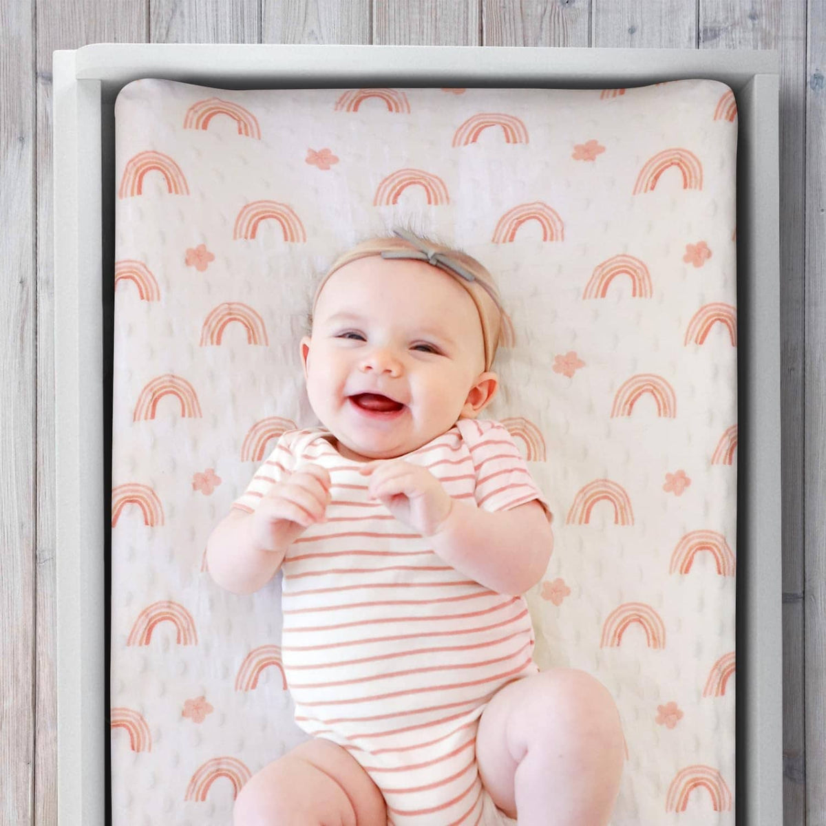 White changing pad cover with orange rainbow and small cloud pattern