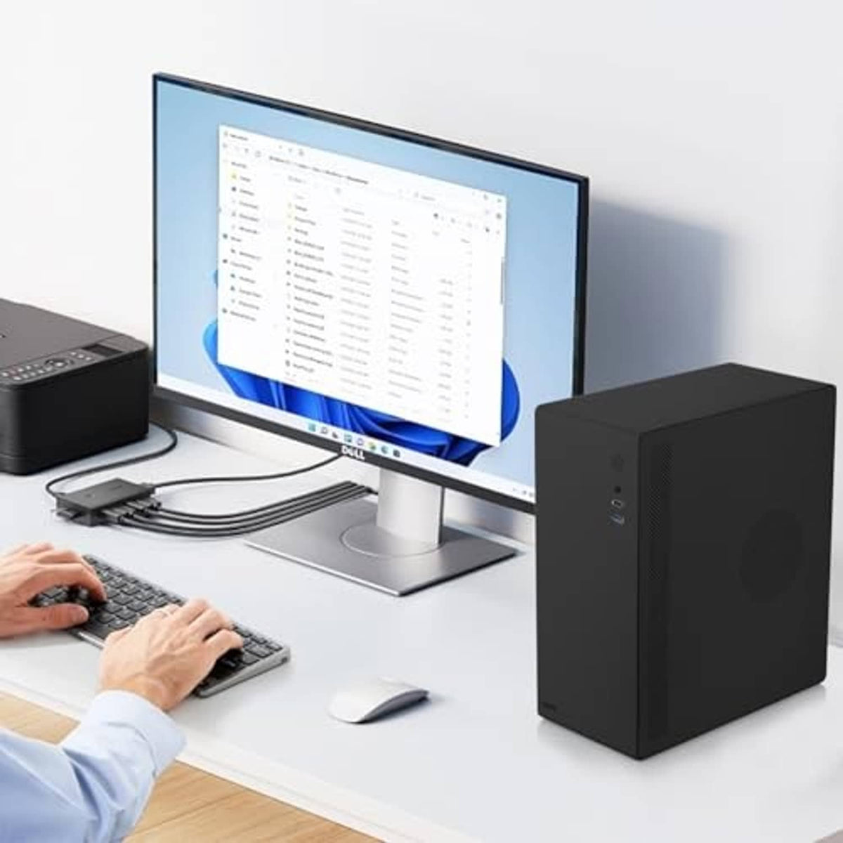 Black mini desktop PC case placed on a desk next to a computer monitor