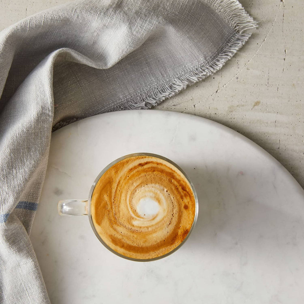 Top view of creamy peanut-butter syrup latte in a glass mug
