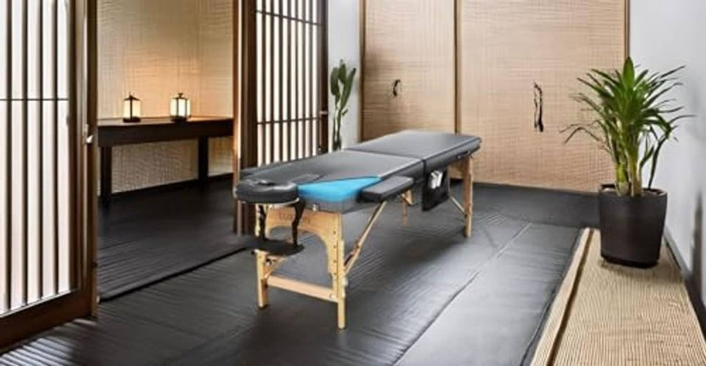 Massage table with blue memory-foam pad, black armrests, wooden legs in a room