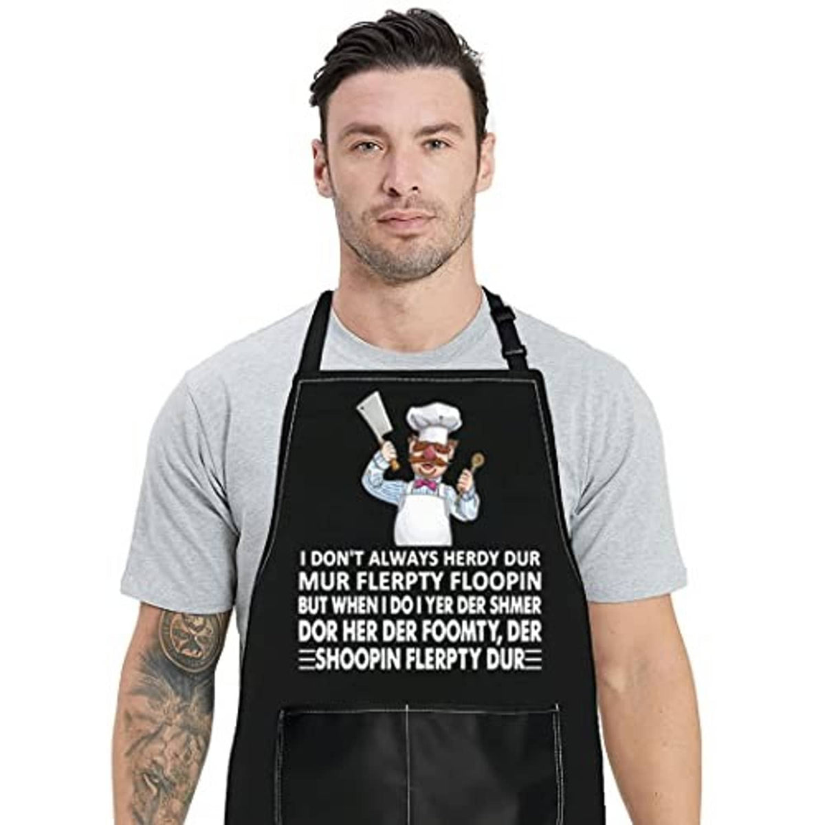 Black chef-themed apron with colorful cook illustration and printed slogan, front pocket.