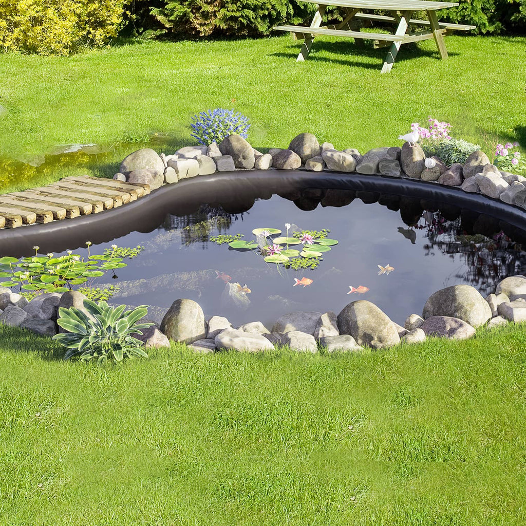 Black pond liner creating a finished backyard fish pond with plants and stones