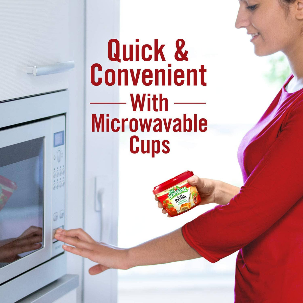 Woman holding a microwaveable beef ravioli cup in a red-lidded container
