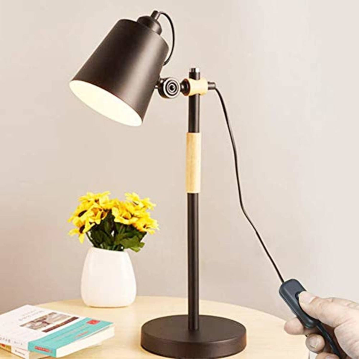 Black inline cord on/off switch attached to a lamp cord, hand pressing button