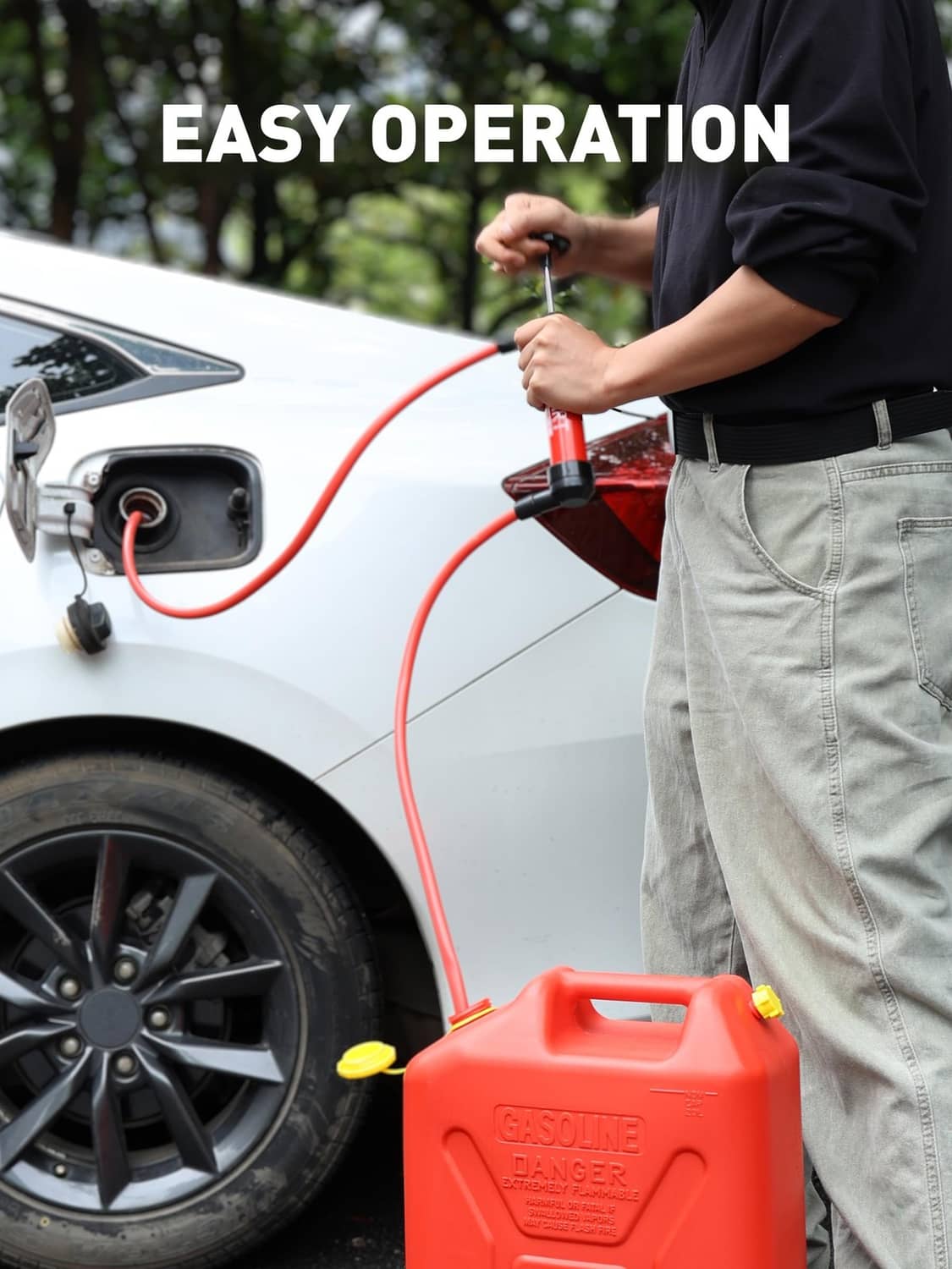 Red hand transfer pump with hoses connected near a car fuel inlet