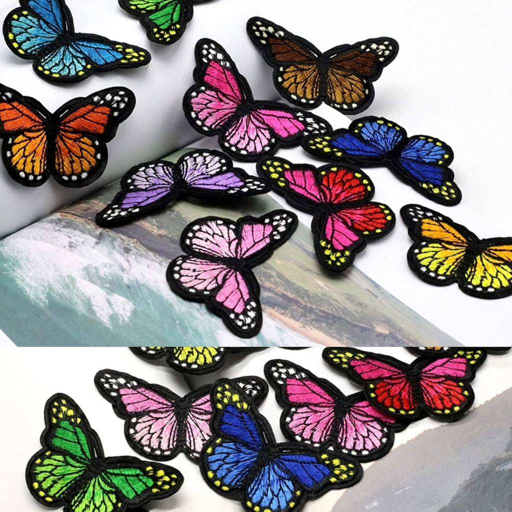 Multiple embroidered butterfly iron-on patches laid on fabric in bright colors