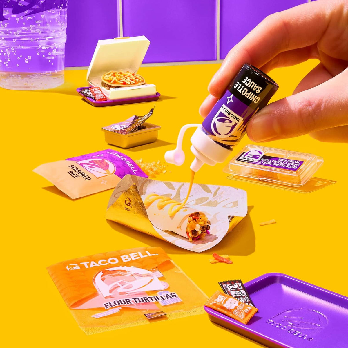 Mini Taco Bell accessories on table: squeeze bottles, food packs, and small tortilla items