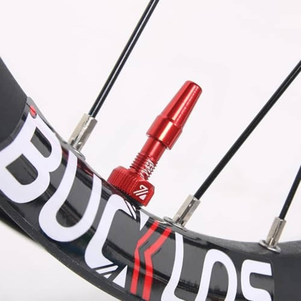 Red Presta valve stem installed on bicycle rim with core exposed