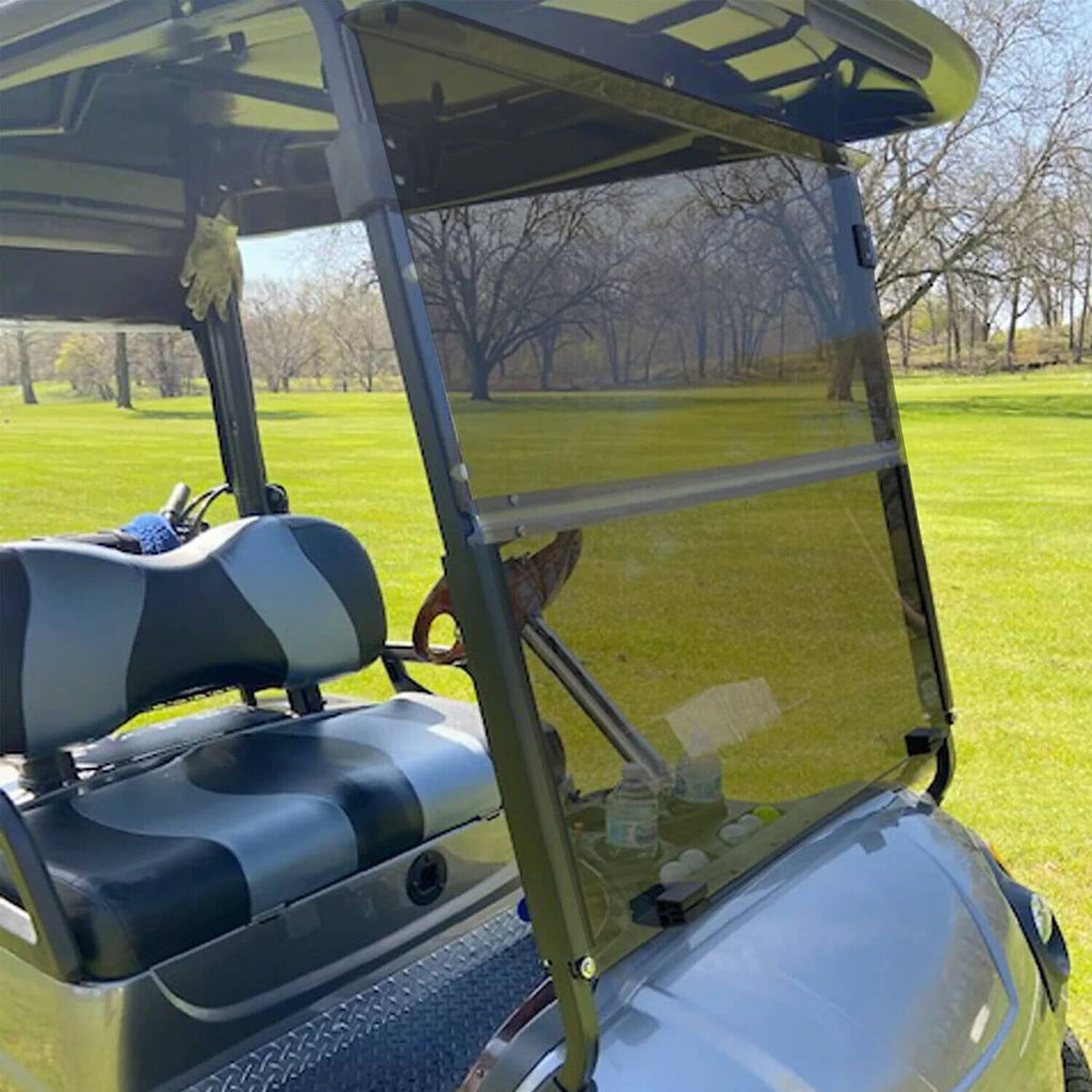 Tinted folding golf cart windshield panel with metal frame on dashboard