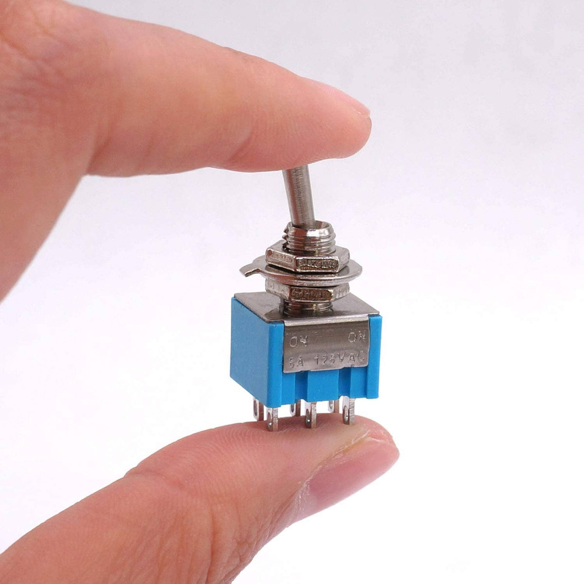Mini DPDT toggle switch with blue base and metal lever, hand-held close view