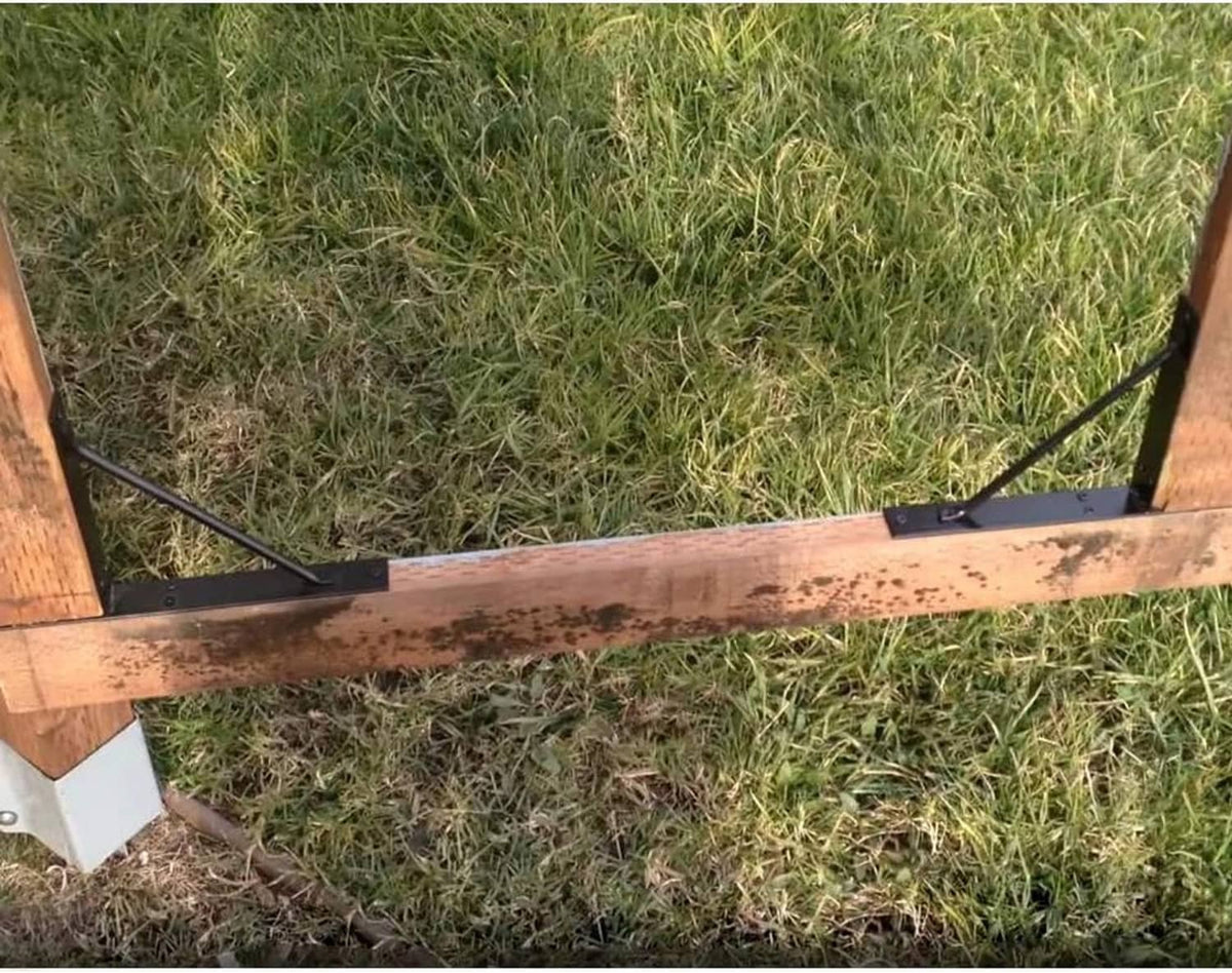 Black no-sag corner brace brackets securing a gate frame against sagging