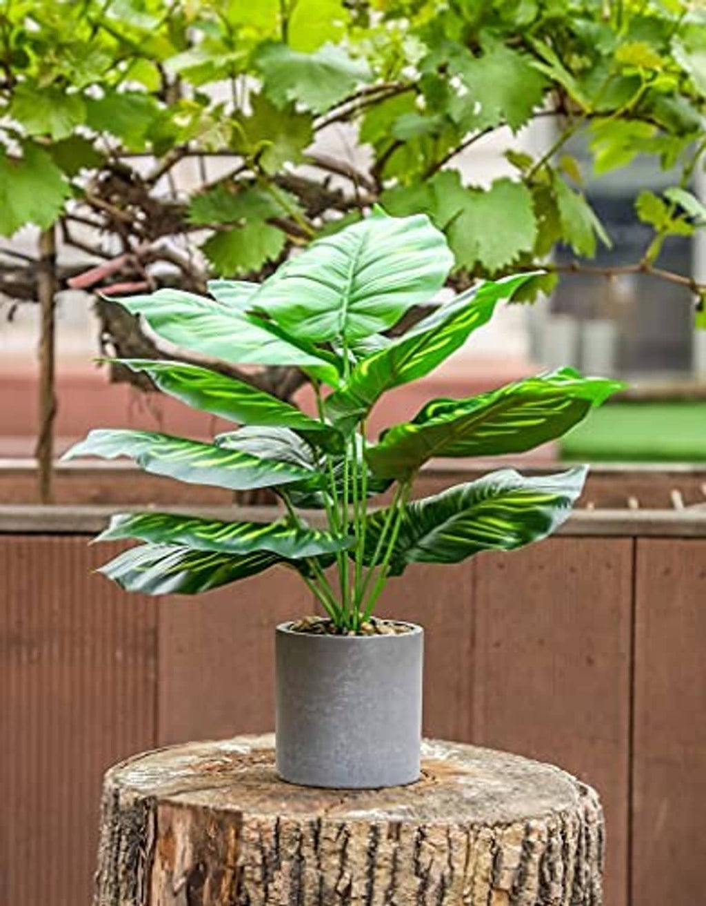 Artificial potted tropical plant with green broad leaves on a gray pot