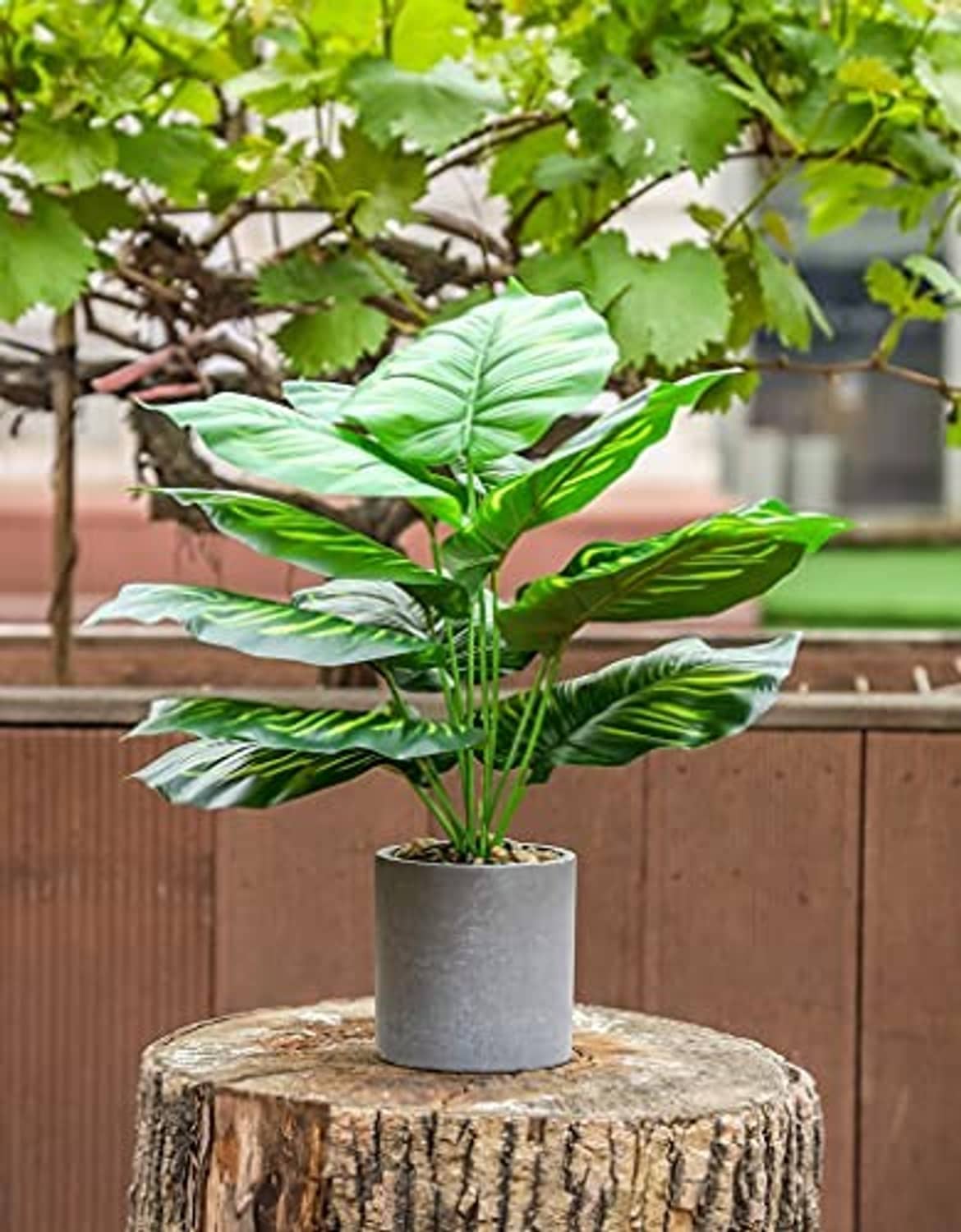 Artificial potted tropical plant with green broad leaves on a gray pot
