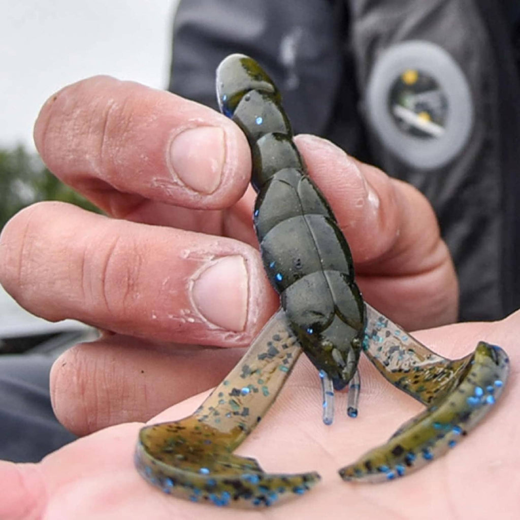 Soft plastic craw bait held in hand, dark green body with yellow speckled claws