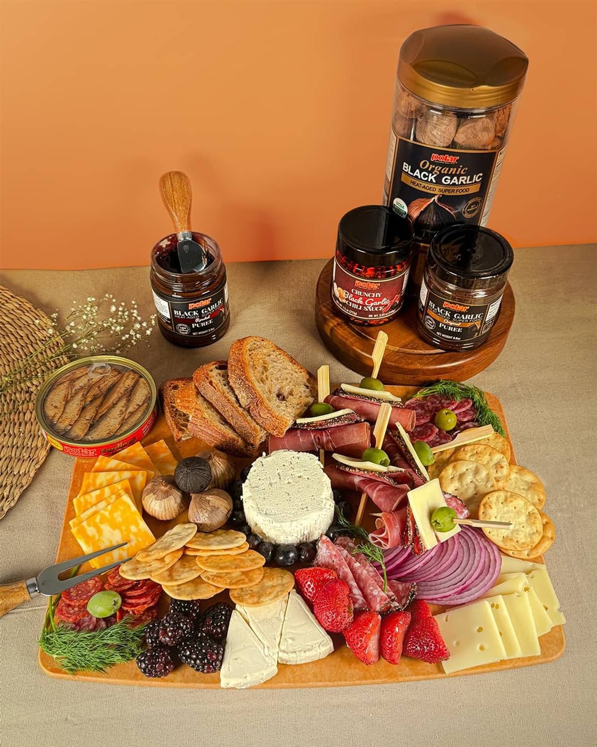 Organic black garlic jars with whole bulbs on a cheese and charcuterie platter