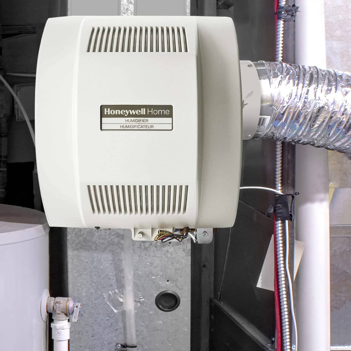 Whole-home humidifier mounted on equipment with vented grille and visible wiring