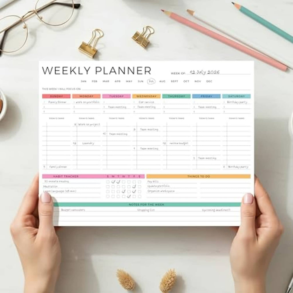 Weekly planner notepad with colorful weekly grid, held open by hands, tear-off 8.5x11
