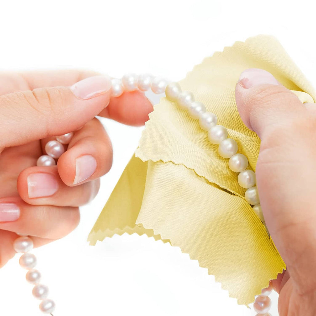 Yellow jewelry cleaning cloth wiping a pearl necklace