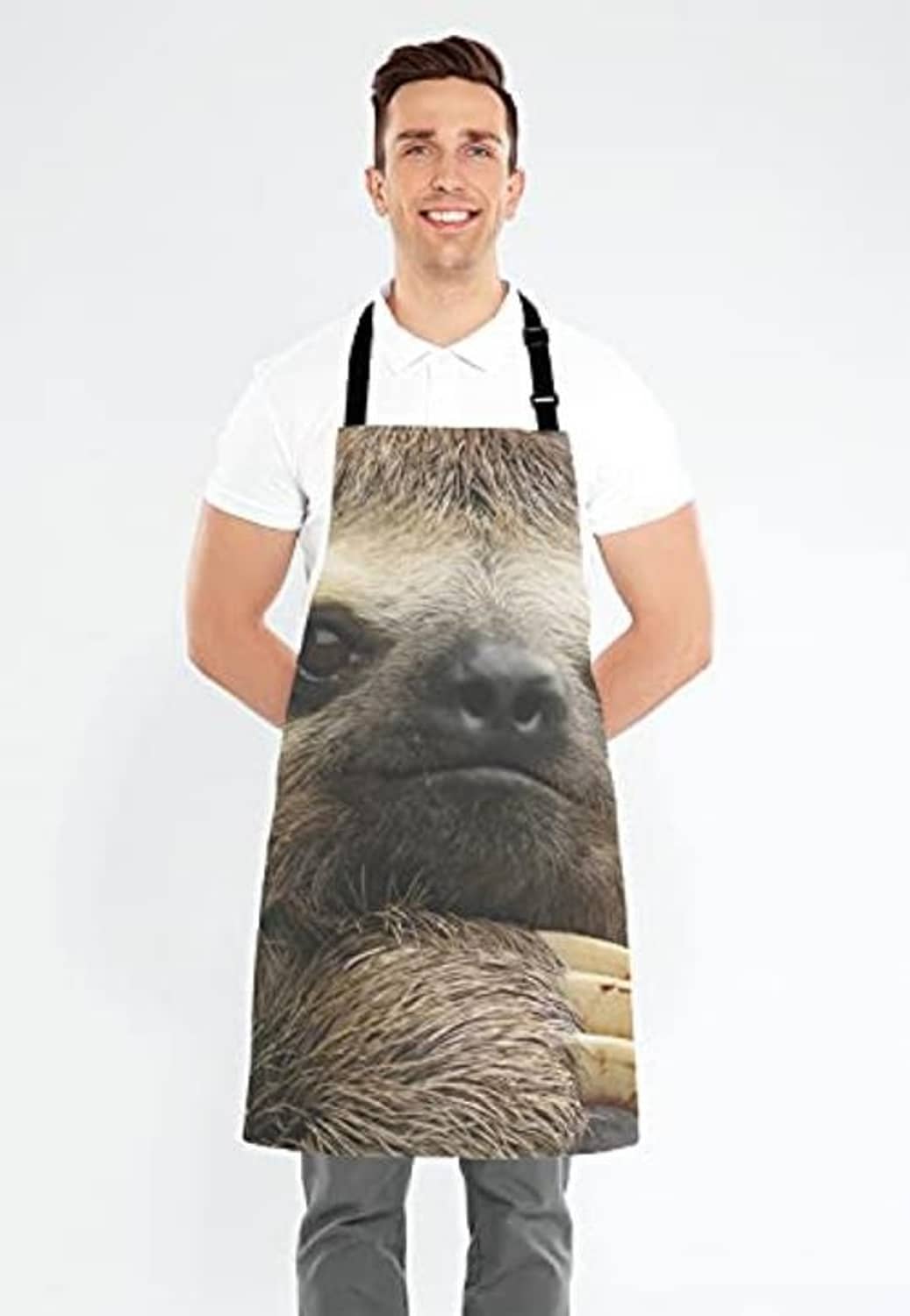 Sloth-print cooking apron on person wearing white shirt, black neck straps and front ties