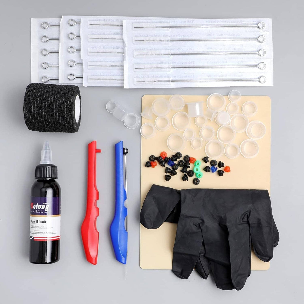 Tattoo kit accessories set with black gloves, ink bottle, needle trays, and rubber grip wrap