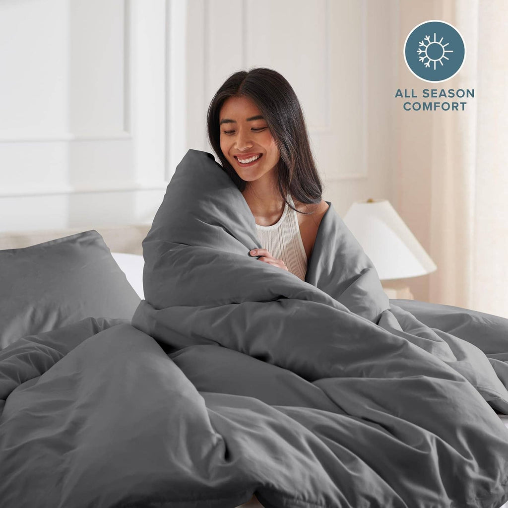 Dark gray duvet cover draped over comforter, woman holding blanket on bed.