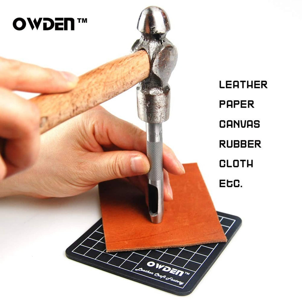 Hand holding a silver hollow punch tool over orange material on a cutting mat