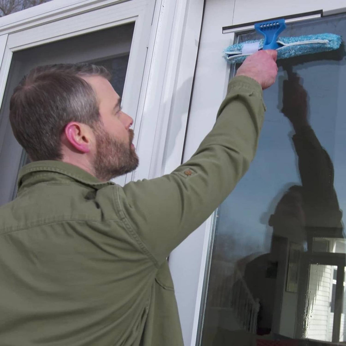 Window cleaning tool with blue microfiber refill sleeve attached, on a glass window