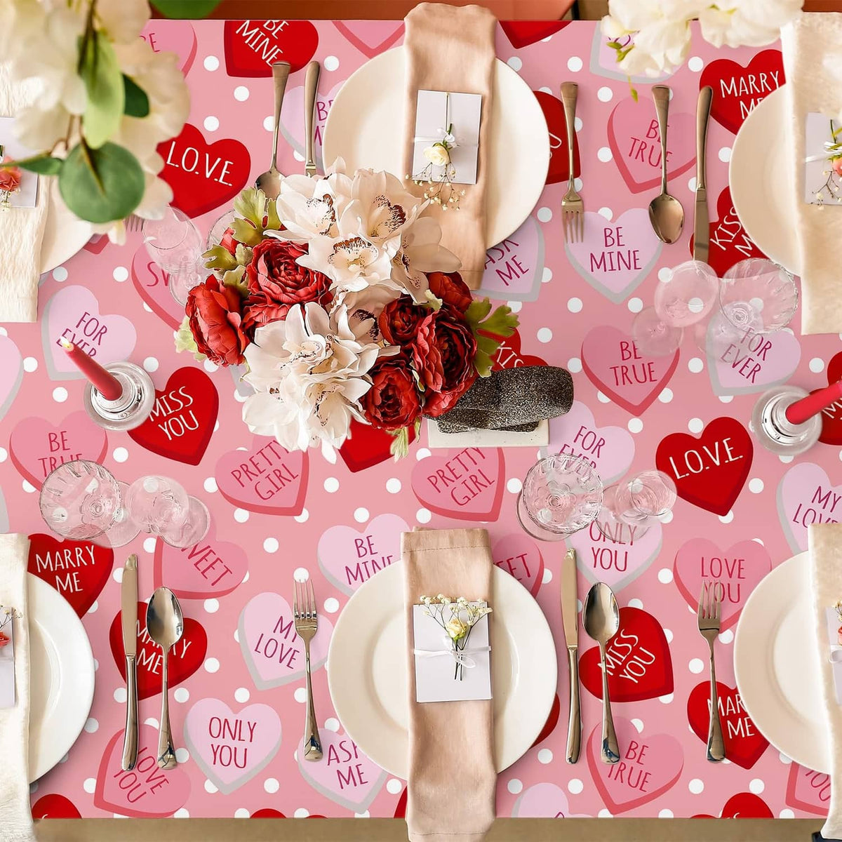 Pink tablecloth flat lay with red hearts, white dots, and assorted Valentine-themed icons
