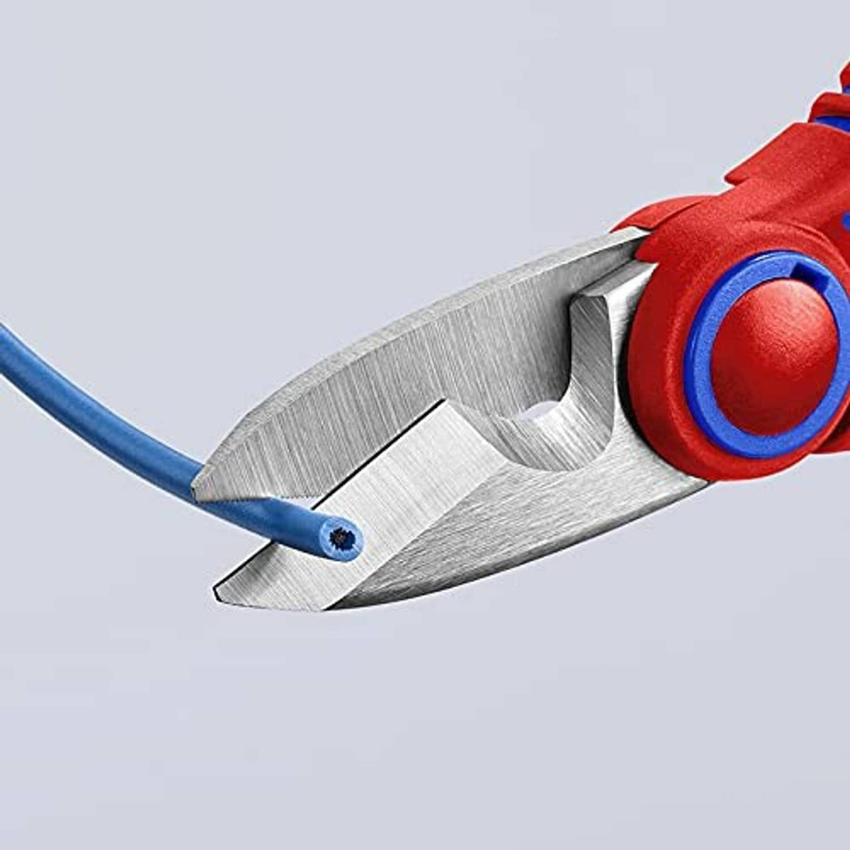 Close-up of electricians' shears blade edges, red handle ring with blue grip trim