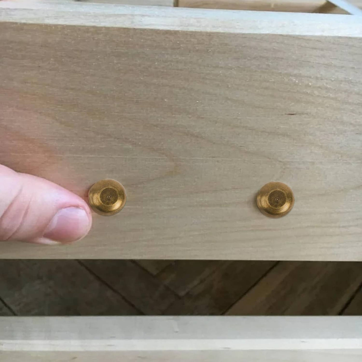 Two bronze screw caps installed on a light wooden panel
