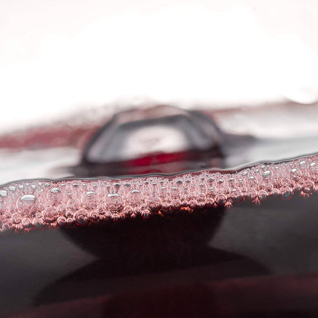 Close-up of red wine surface with bubbles inside the decanter