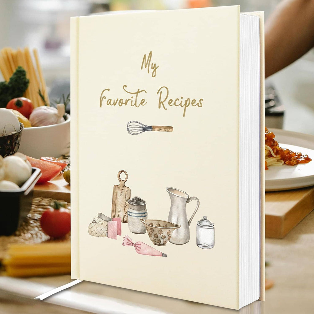Cream hardcover recipe book on table, “My Favorite Recipes” and illustrated cooking items