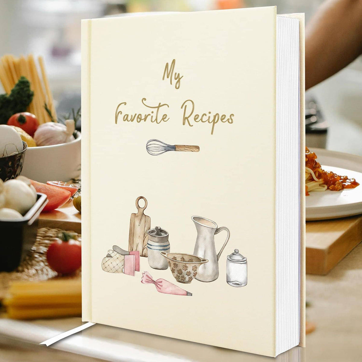 Cream hardcover recipe book on table, “My Favorite Recipes” and illustrated cooking items