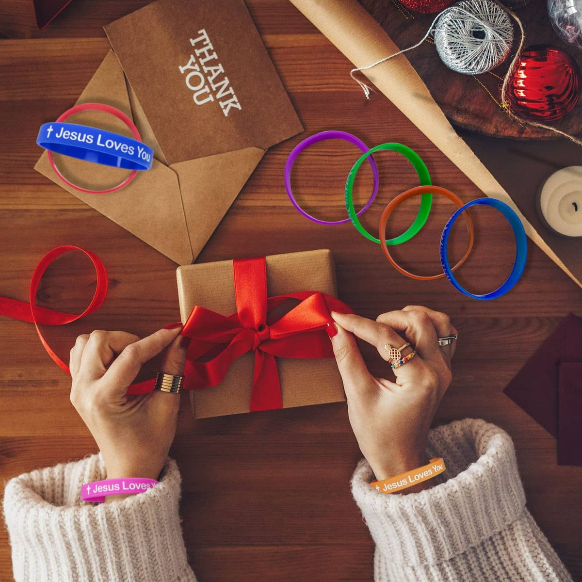 Colorful silicone wristbands with “Jesus Loves You” print while tying a gift