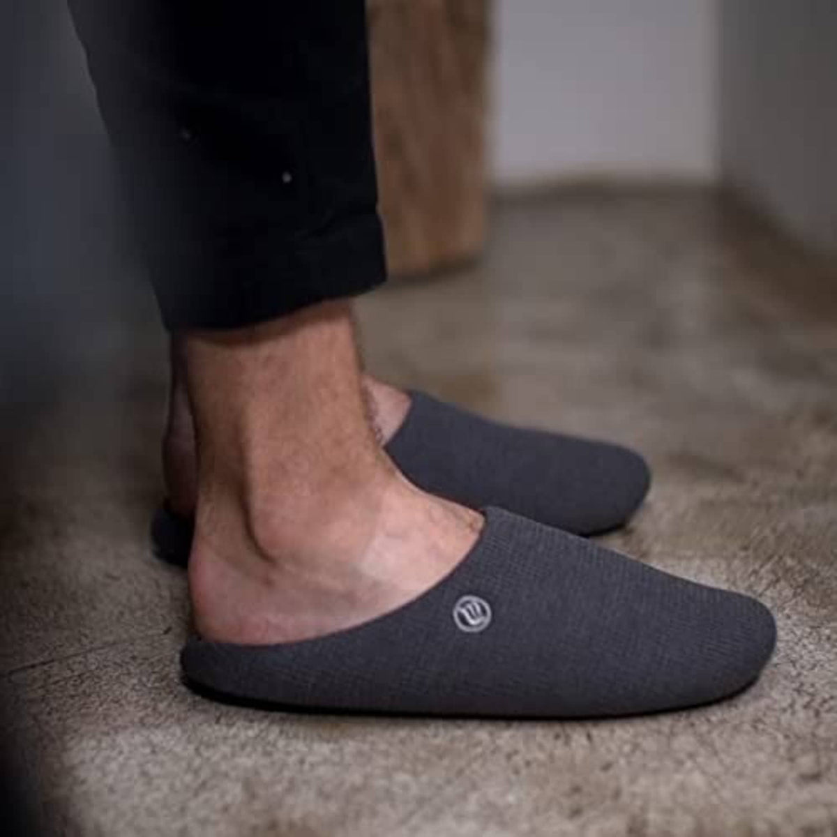 Feet wearing dark blue slip-on slippers with cushioned footbed