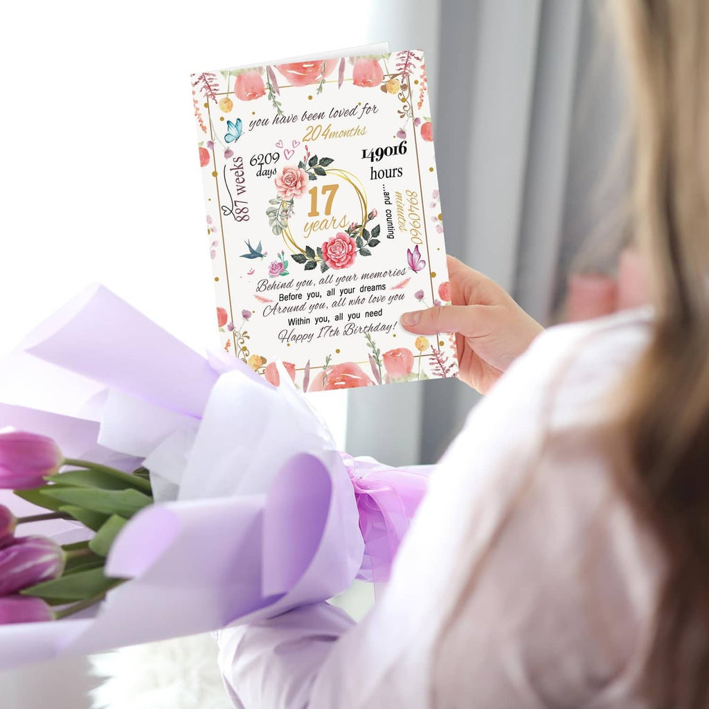 Hand holding 17th birthday floral card with gold “17 years” and rose details