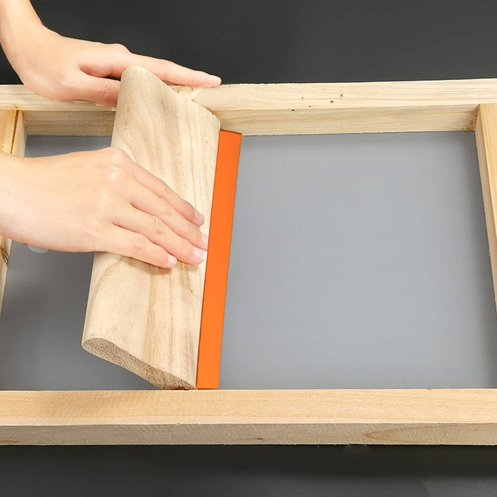 Wood screen printing frame with mesh; hands secure fabric with orange tape