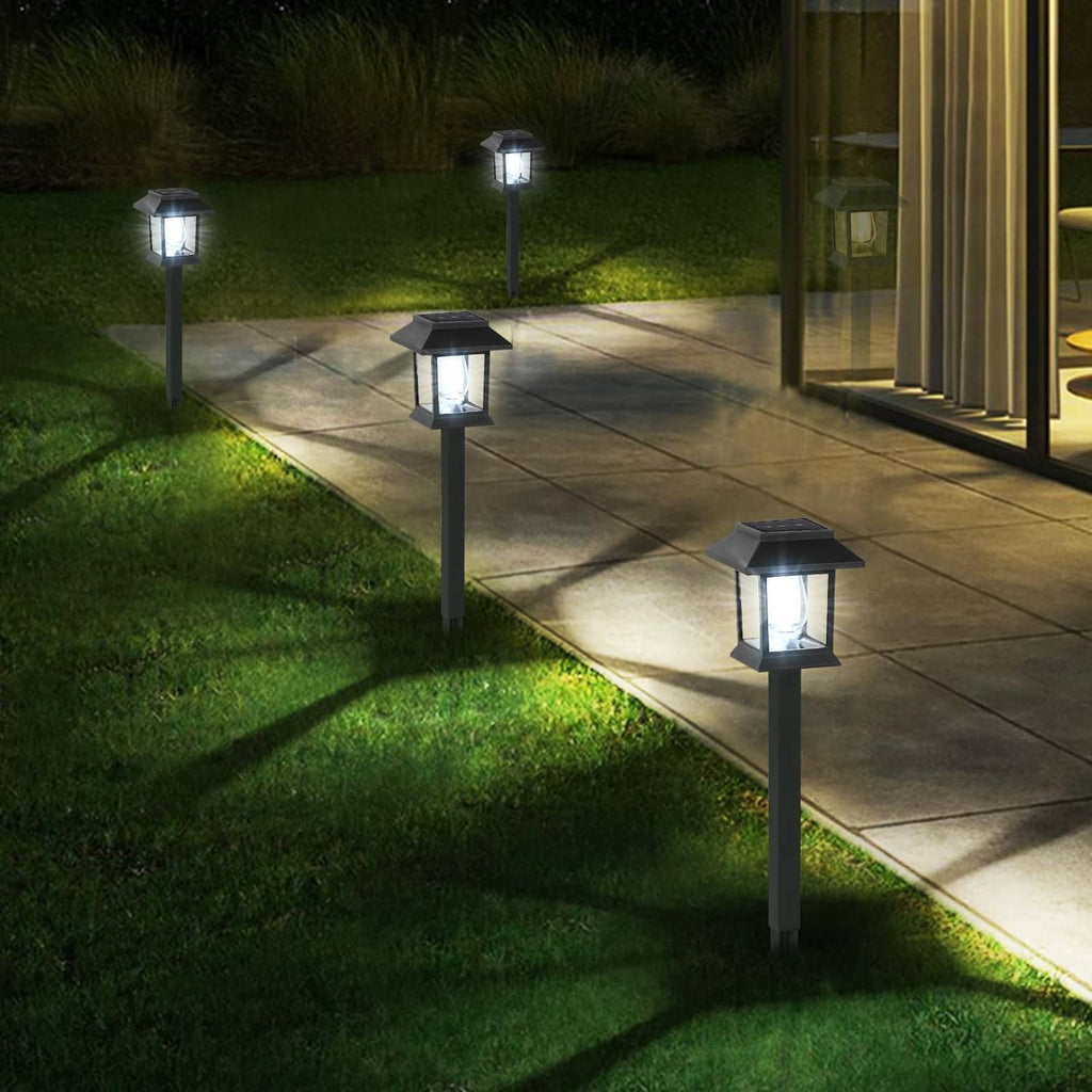 Outdoor solar pathway lights in a line along concrete walkway, black lanterns glowing cool white