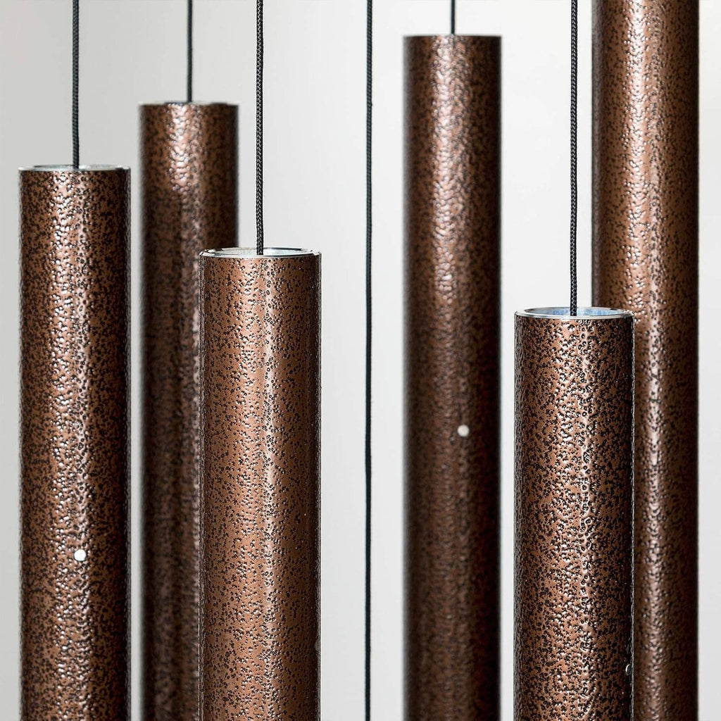 Bronze-copper wind chime rods with textured finish, hanging from metal frame