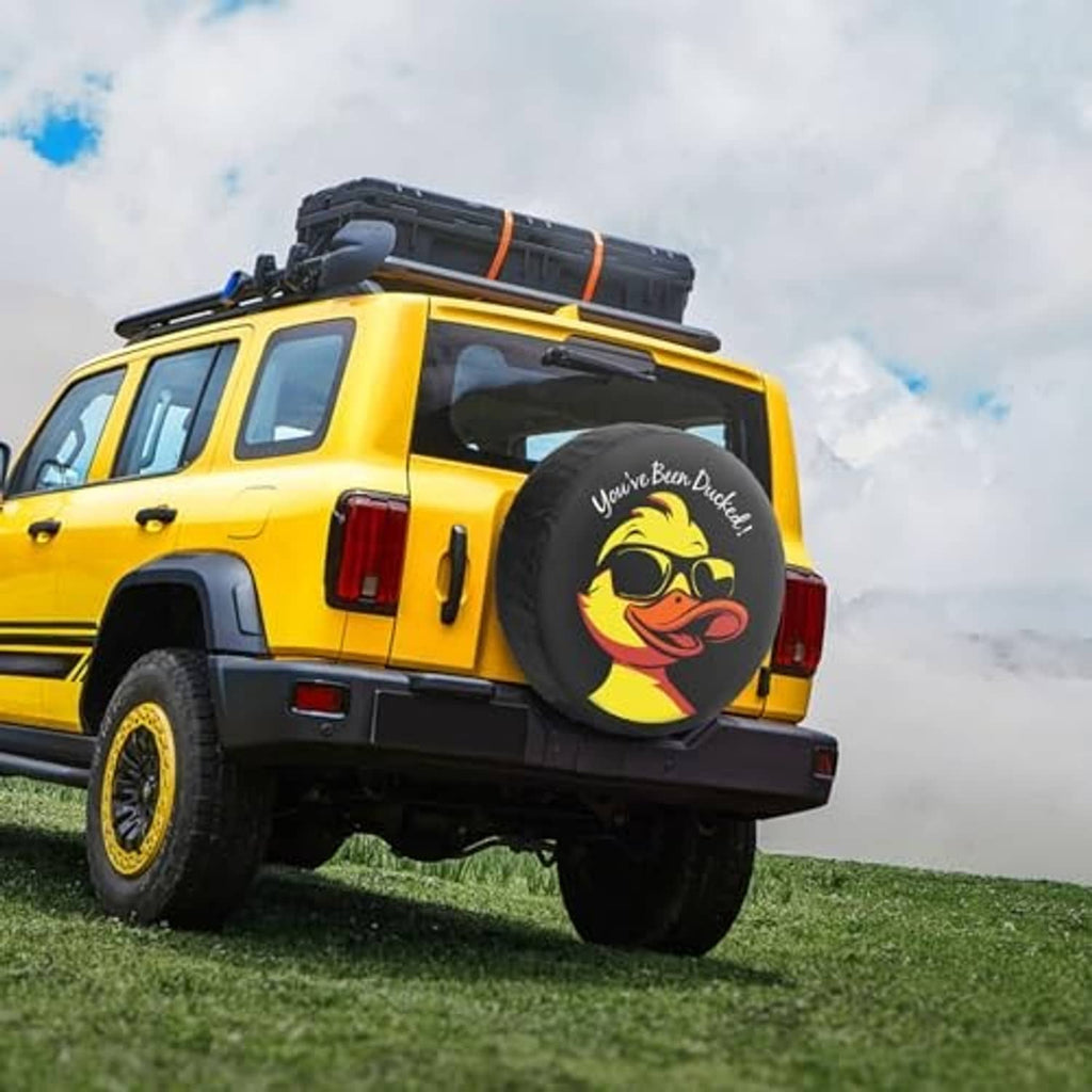 Spare tire cover on a yellow SUV: black duck face graphic on round cover