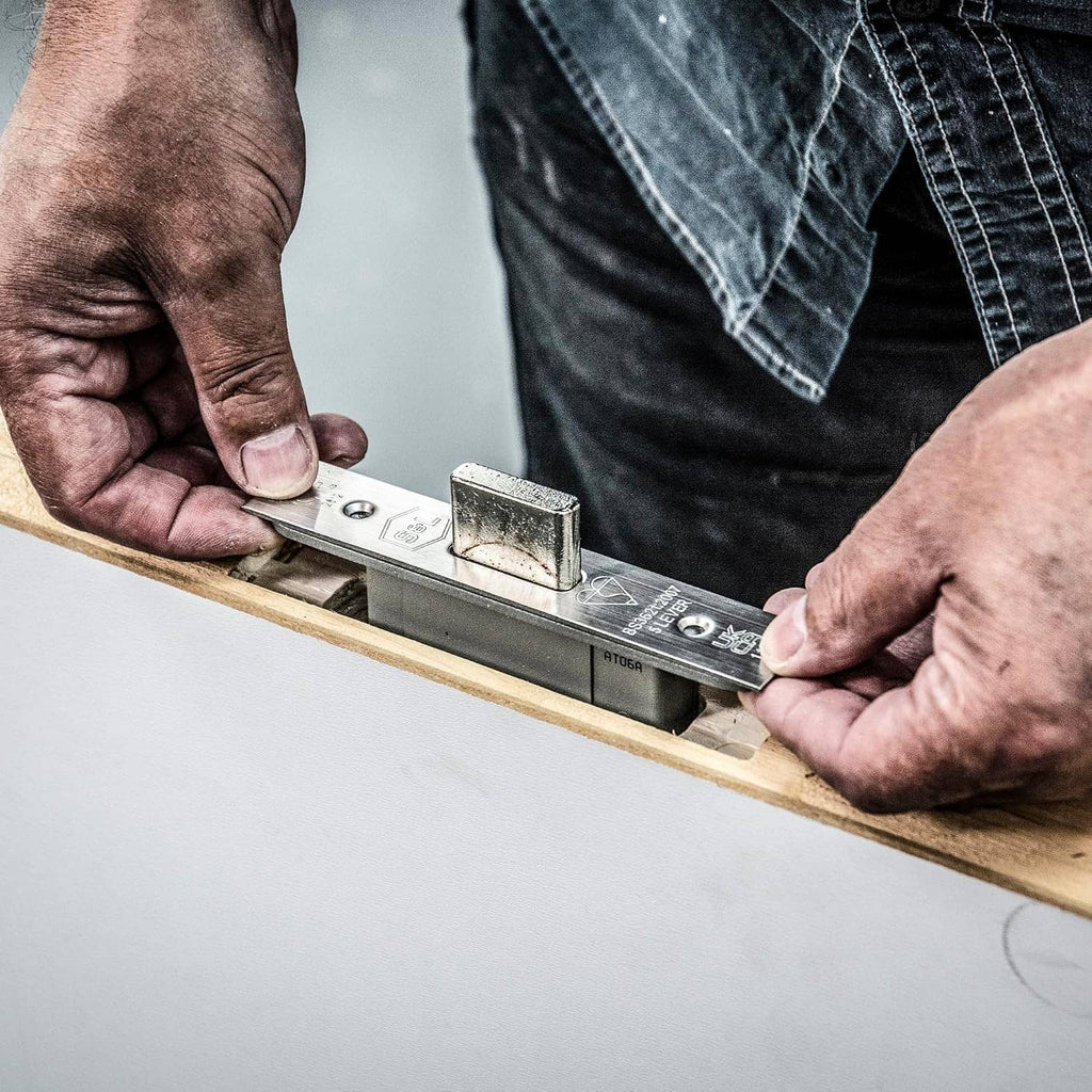 Adjustable lock jig tool with metal base and guide, clamped on a door frame during use