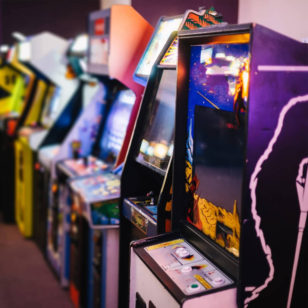 Arcade game cabinet row with illuminated screens and control panels