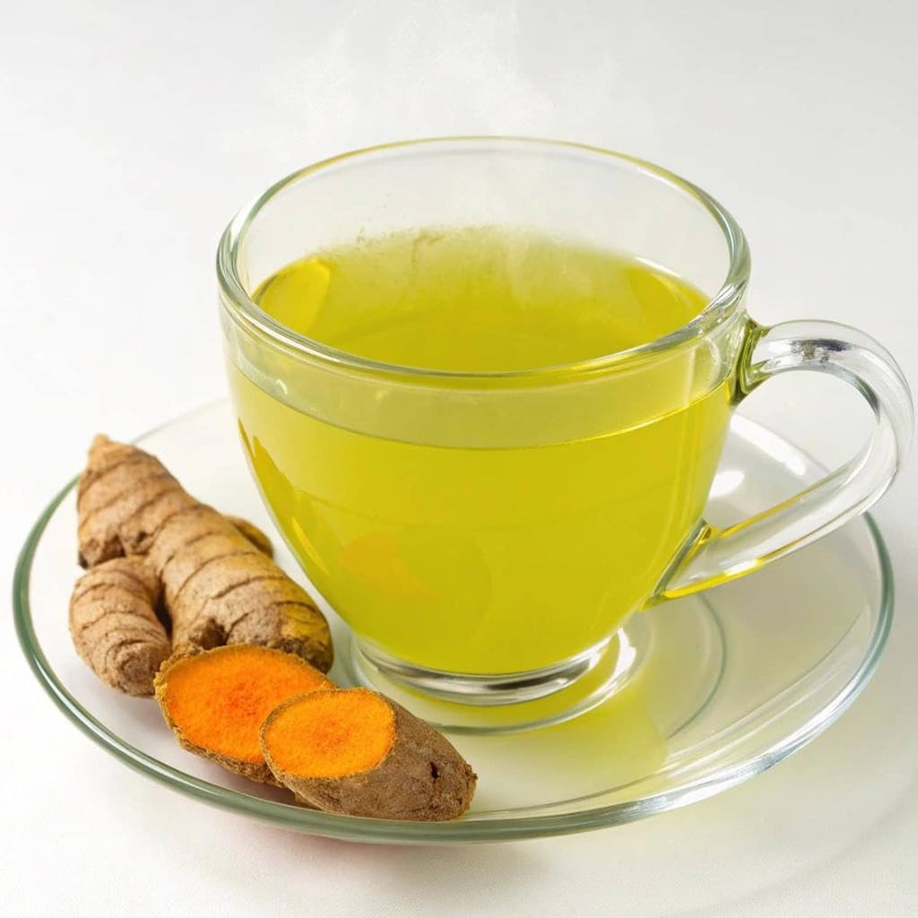 Glass cup of green matcha tea with turmeric pieces on a saucer