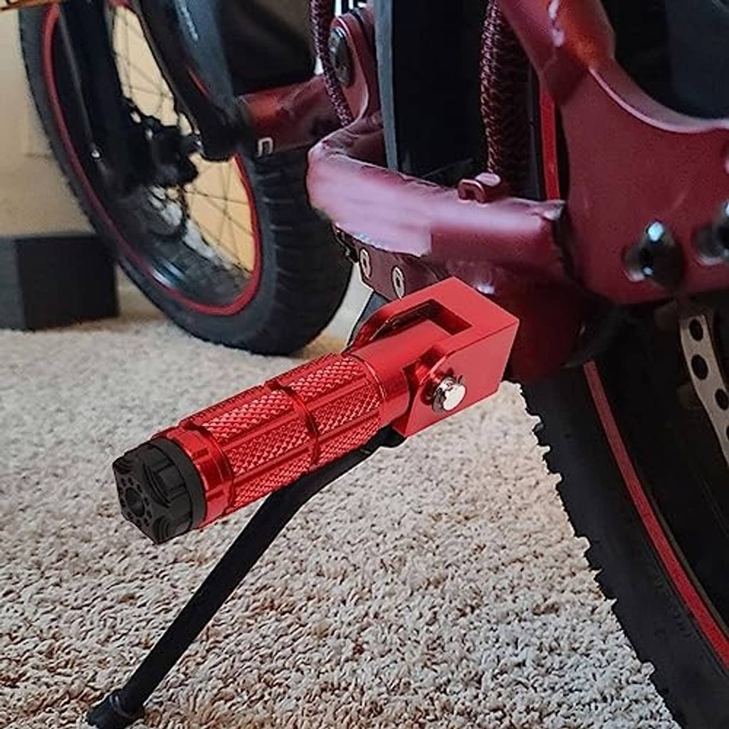 Red foldable motorcycle foot pegs with textured grips and black end caps installed on bike