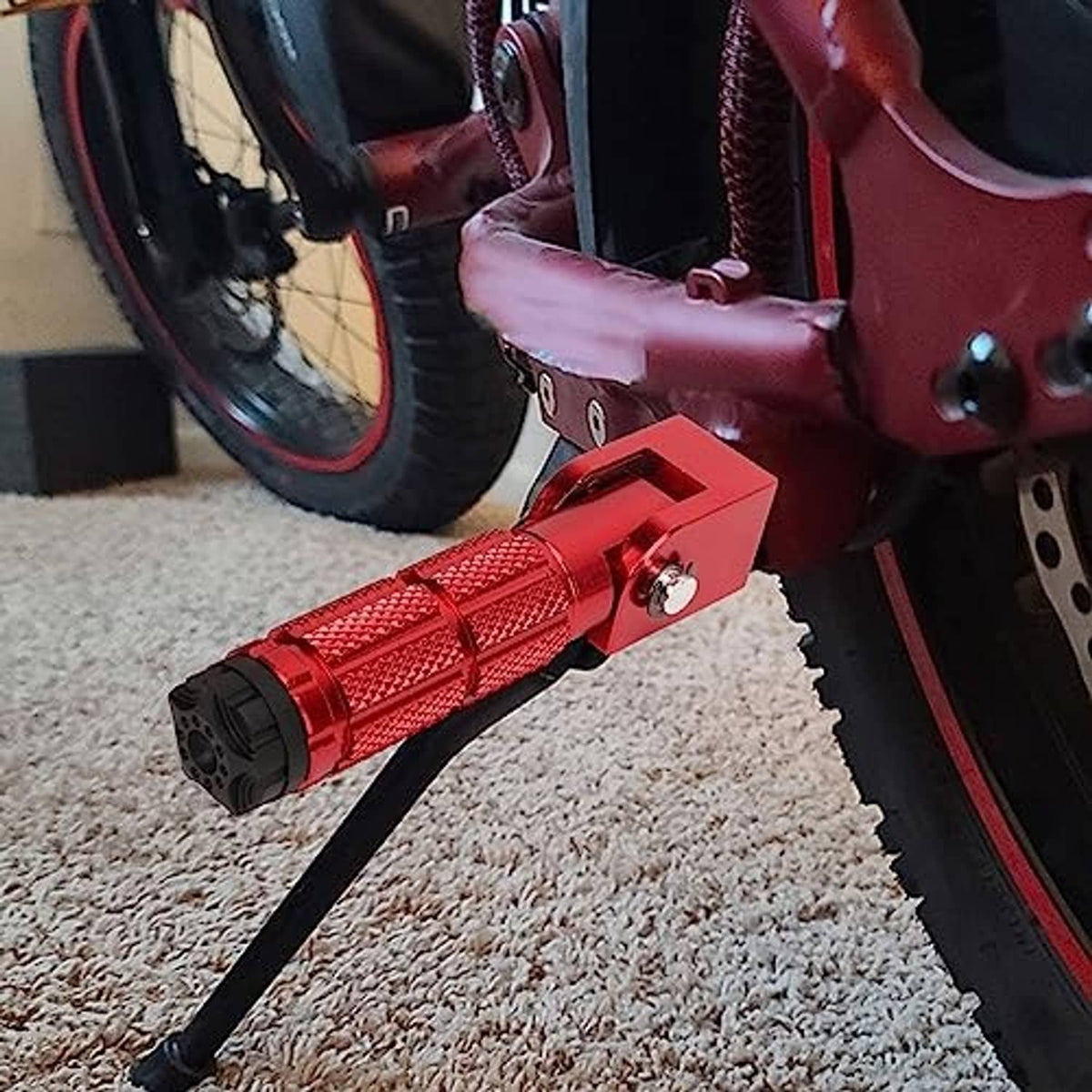 Red foldable motorcycle foot pegs with textured grips and black end caps installed on bike
