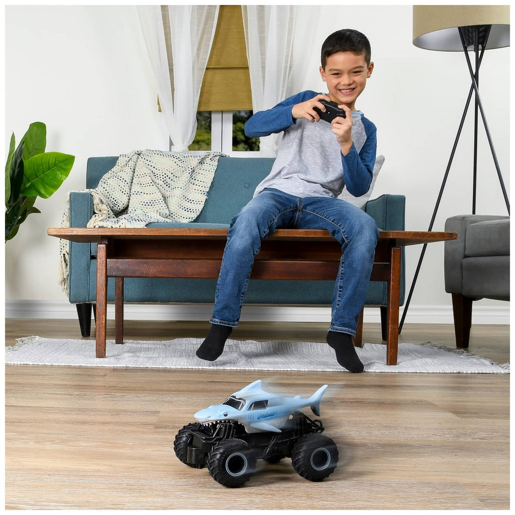 Shark-themed RC monster truck on floor while a boy holds the black controller