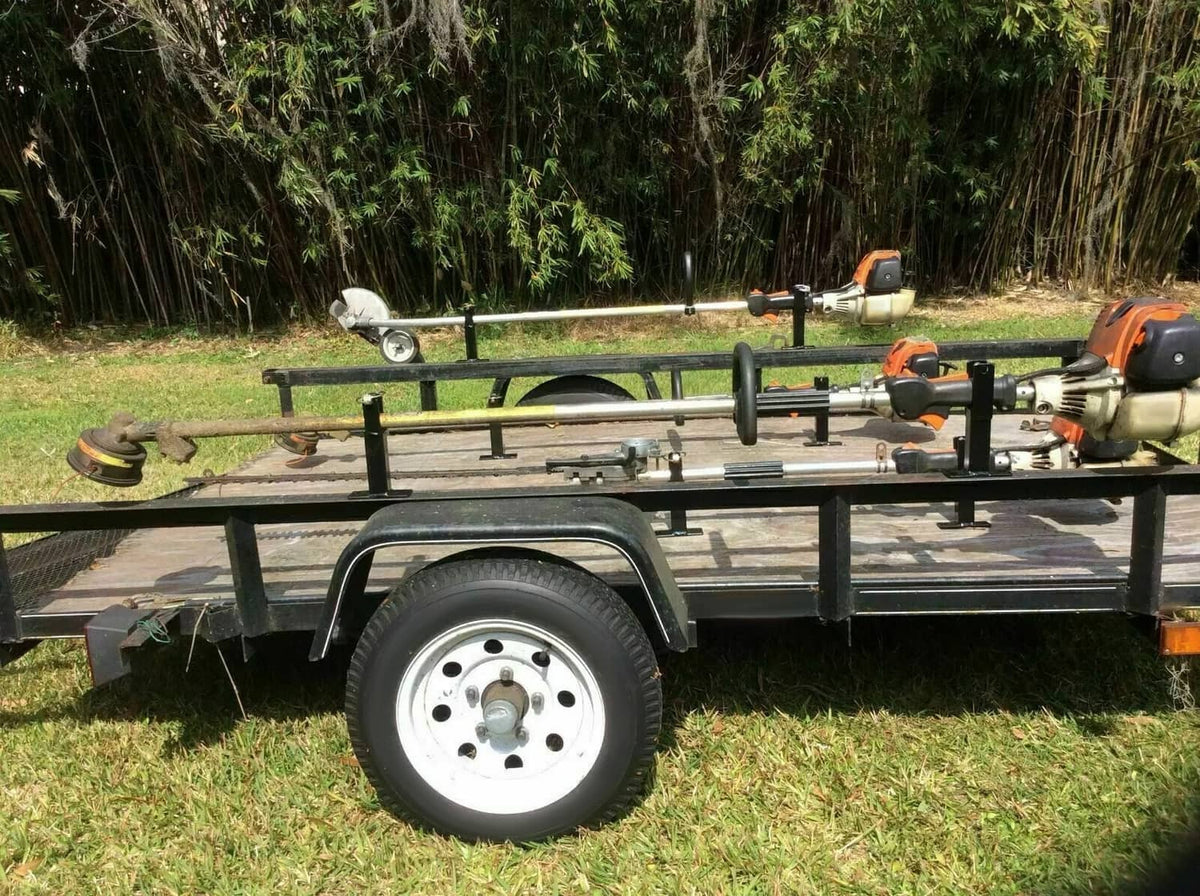 Trailer-mounted black rack holder brackets with posts along the tool carrier frame