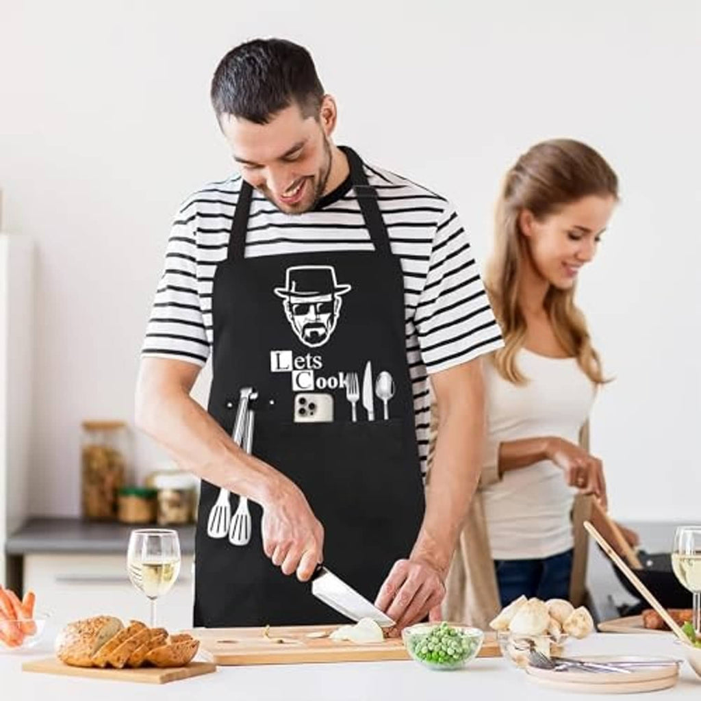 Black 'Lets Cook' apron on man in striped shirt; chef-hat face and utensil graphic